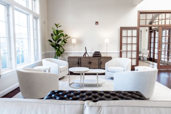 a living room with white furniture and large windows at Broadlands Apartments in Ashburn, VA 20148